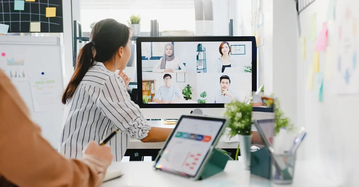 Employees participating in a virtual team meeting in a hybrid work model office