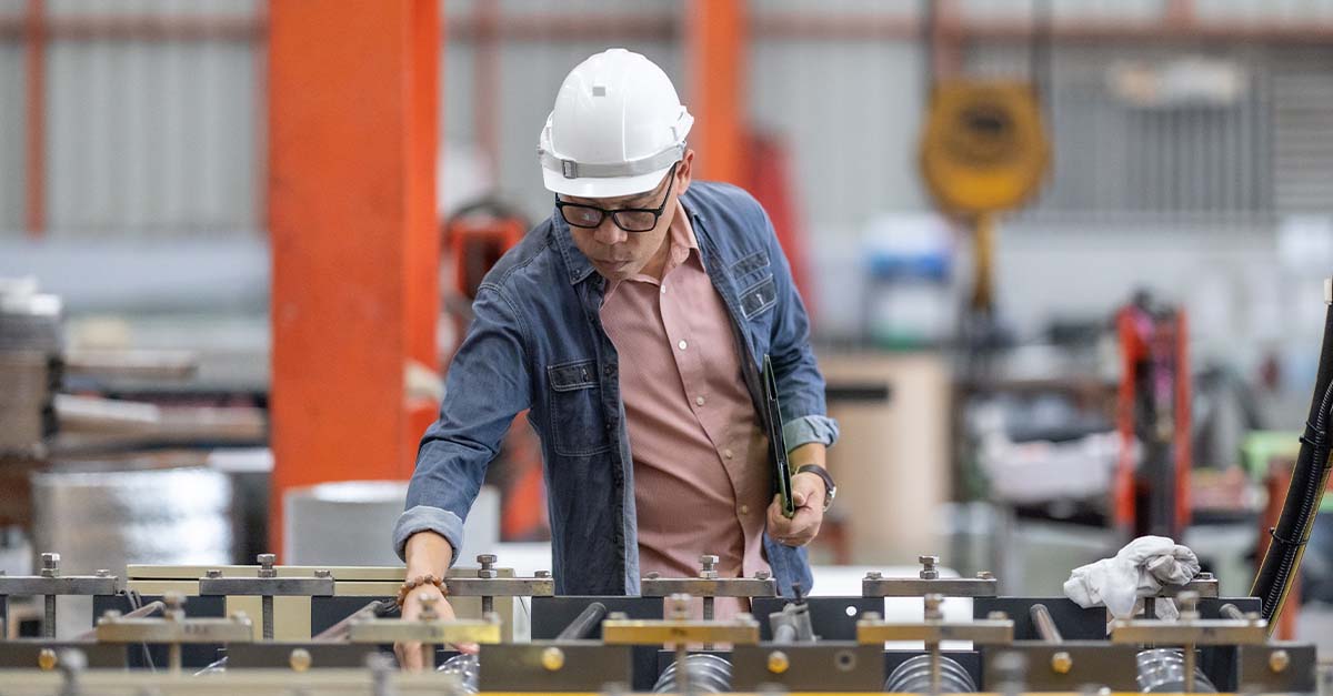 Man with a white hard hat working in a manufacturing environment 