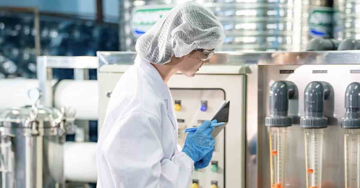 Worker in a lab coat inspecting machinery in an industrial facility